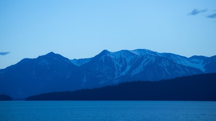 Wall Mural - Silhouetted mountains against a pale blue sky.