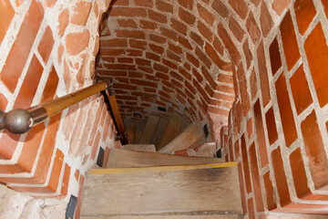 A wooden staircase leading to the bottom among the red brick walls