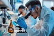 © Nognapas - Young scientists conducting research investigations in a medical laboratory, a researcher in the foreground is using a microscope