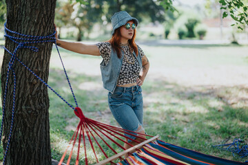 confident young woman enjoying a sunny day outdoors, standing near a colorful hammock in a peaceful 