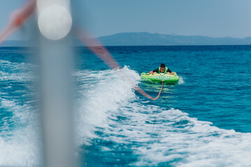 Summer speedboat tubing adventure on the sea with clear blue water and a green inflatable