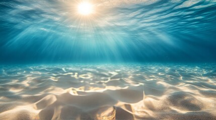 Seabed sand with blue tropical ocean above, empty underwater background with the summer sun shining brightly, creating ripples in the calm sea water