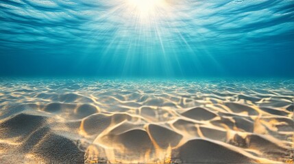 Seabed sand with blue tropical ocean above, empty underwater background with the summer sun shining brightly, creating ripples in the calm sea water