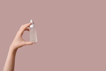 Wall Mural - Hand of woman with bottle of cosmetic oil on pink background