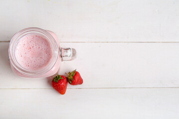Wall Mural - Mason jar of tasty strawberry smoothie on light wooden background