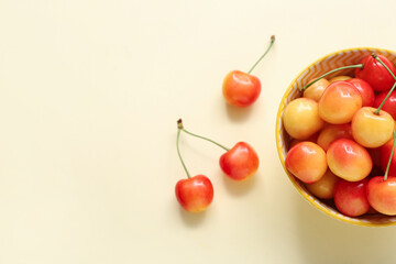 Bowl with fresh yellow cherry on beige background, closeup