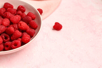 Bowl with fresh raspberries on pink background