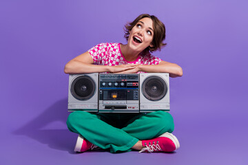 Sticker - Full size photo of impressed woman dressed print t-shirt sit with boombox look at promo empty space isolated on violet color background