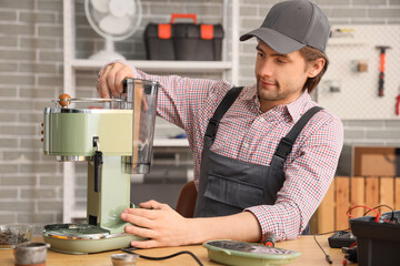 Wall Mural - Male worker repairing coffee machine at table in workshop