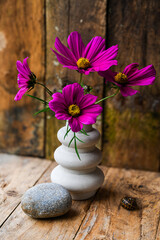 Wall Mural - A vase with purple flowers sits on a wooden table beside a rock. The flowers are arranged in a way that they are all facing the same direction, creating a sense of harmony and balance