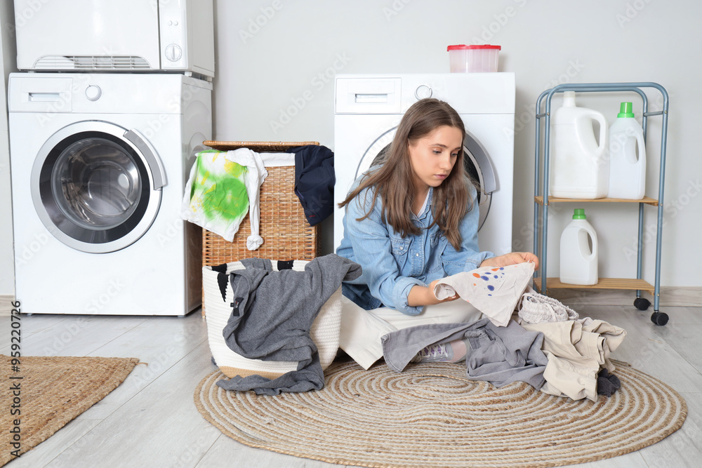 Young woman sorting dirty clothes in laundry basket at home