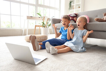 Wall Mural - Cute little children watching cartoons on laptop at home