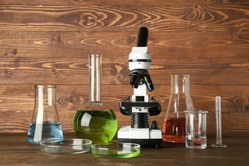 Wall Mural - Microscope and laboratory glassware on wooden background