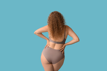 Wall Mural - Beautiful young body positive woman in stylish underwear on blue background, back view