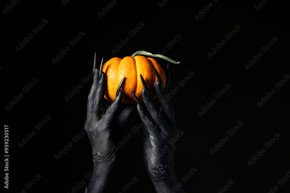 Black hands of witch with fresh pumpkin on dark background. Halloween celebration
