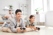 © Pixel-Shot - Teenage boy with his sister and father playing video game at home