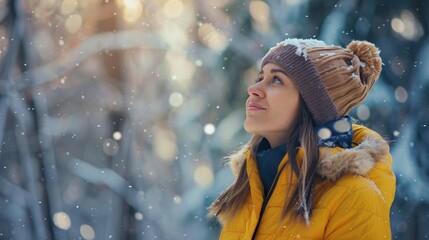 beautiful young woman with yellow coat in a snow forest looking up in winter