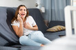 © JackF - Young european woman, sitting on a sofa in an apartment, talking on a mobile phone with someone