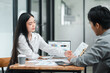 © Satori Studio - Two colleagues in a modern office setting discussing financial reports and data analysis during a business meeting.