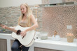© ultramansk - A musician woman plays an acoustic guitar in a bright kitchen, combining the themes of domestic life and artistic expression, reflecting a relaxed lifestyle focused on creativity and comfort.