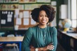 © Baba Images - Smiling portrait of a young black female teacher in classroom