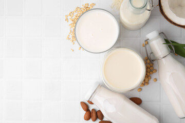 Poster - Different types of vegan milk and ingredients on white tiled table, flat lay. Space for text