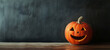 © Mrt - Jack-o’-lantern carved halloween pumpkin with a smiley face on chalkboard, wooden surface, against dark textured background, halloween themed painting with copy space for text.