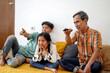 © Queenmoonlite Studio - Side View Of Cheerful Asian Family Watching Movie At Television While Sitting On The Floor