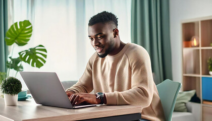 A young man operating a laptop. Image material of a young, smiling man operating a laptop.