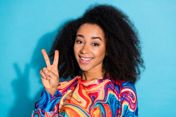 Wall Mural - Photo portrait of beautiful curly hair woman in trendy sweatshirt showing v sign greetings hello isolated on blue color background