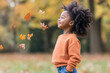 © Aris - African little girl smiling wearing sweatshirt playing at sunny autumn park