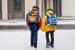 © Irina Schmidt - Two little kids boys of elementary class walking to school during snowfall. Happy children having fun and playing with first snow. Siblings and best friends with backpack in colorful winter clothes.