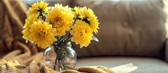 Poster - Close up of a bouquet of stunning yellow dahlia flowers in a glass vase with a brown textile couch in the background Copy space close up natural light