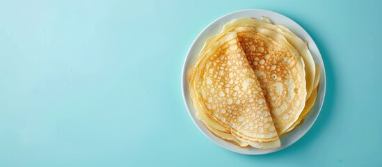 Poster - Crepes thin Russian pancakes on a white plate set against a pastel blue background Top view. Copy space image. Place for adding text and design