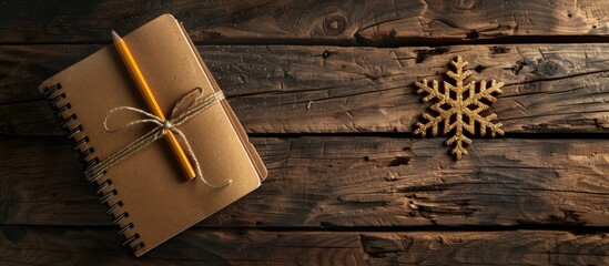 Poster - There is a diary a pencil and a golden snowflake on a wooden surface. Copy space image. Place for adding text and design