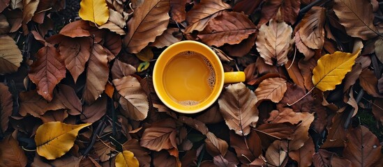 Sticker - Flat lay arrangement featuring a yellow coffee cup set against a backdrop of autumn leaves Invokes a cozy autumn atmosphere Top view copy space selective focus