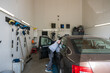© Cavan - Side view of young male mechanic examining car at auto repair shop