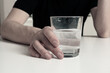 © daniiD - A man suffering from an illness holds a glass with a pill, symbolizing hope for recovery and the fight against the disease