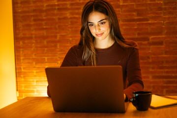 Professional woman working in the evening from her home office on a laptop. The scene captures the essence of modern freelance life, remote work, and digital professionals updating their online 