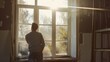 © VK Studio - Sunlight filters through a large window in an old, partially renovated room as a man gazes outside, lost in thought.