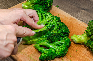 A chef cuts fresh broccoli on a cutting board