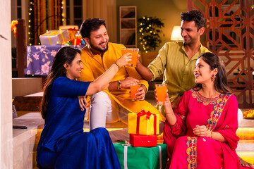 Cheerful Indian couples and friends celebrating Diwali at home with drinks, sweets, taking selfies