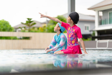 Asian kids girl playing and having fun in swimming pool, Asian children in swimsuit playing in swimming pool