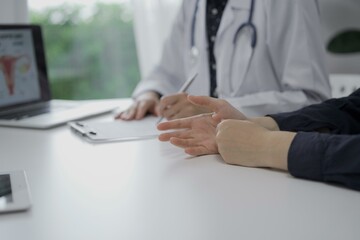 Doctor and a patient in clinic. The female physician is filling up medication history record form, close up of woman hands. Medicine concept