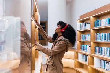 Young woman student searching a book at library