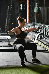 Wall Mural - A plus-size woman exercises with dumbbells in a gym, embodying confidence and fitness.