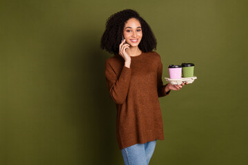 Wall Mural - Photo of nice young woman speak phone coffee wear pullover isolated on khaki color background