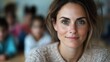 © svastix - A friendly brown-haired woman in a cozy classroom setup with blurred students in the background, depicting a welcoming and nurturing educational environment full of warmth.