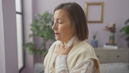 Mature woman with short hair, eyes closed, in a tranquil home setting, exuding a sense of peace and contemplation.