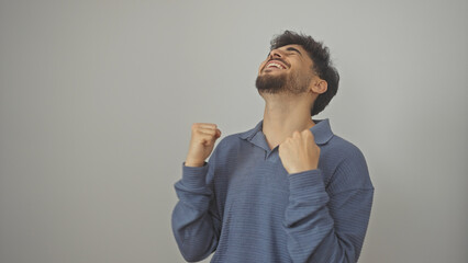 A joyful young man with a beard celebrating success over a white background